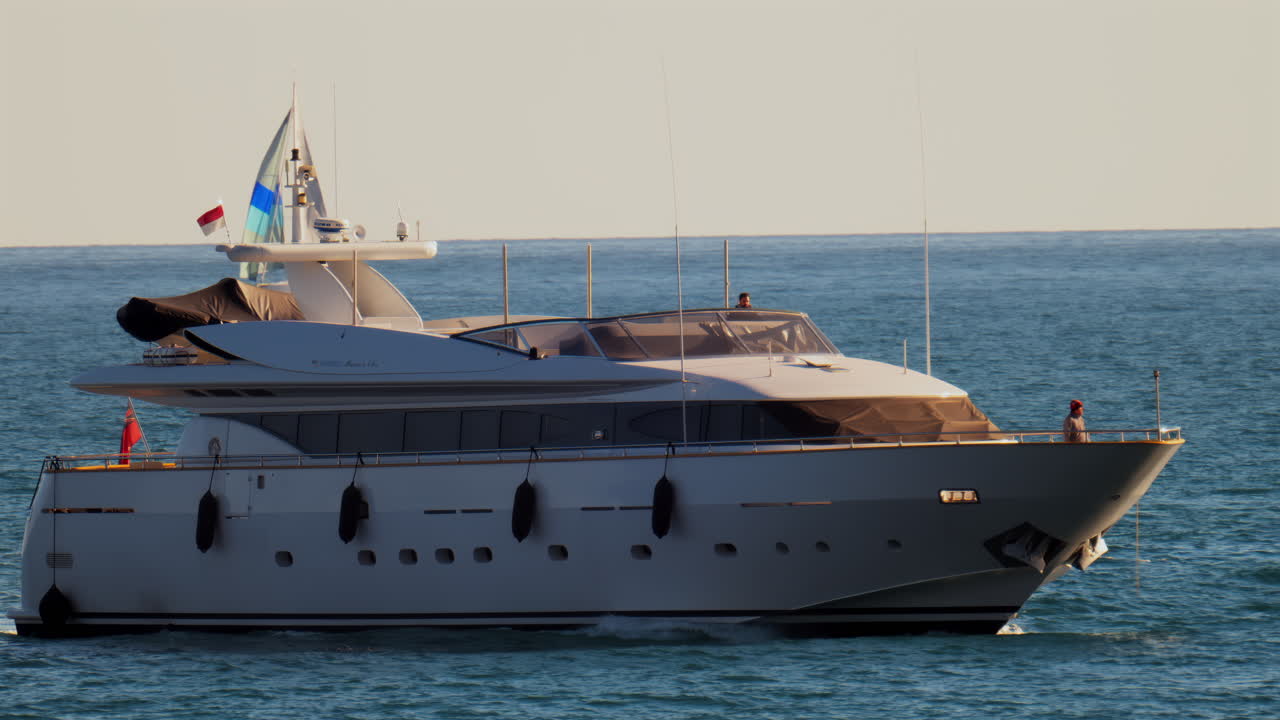 Nizza, Francia - 10 febbraio 2025: una barca con la bandiera di Monaco che si muove sul mare con piccole barche a vela sullo sfondo