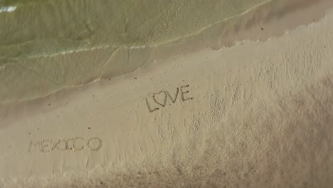 Aerial-crazy-turning-shot-of-LOVE-inscribed-in-the-sand-on-a-beach