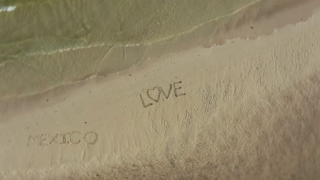 aerial crazy turning shot of love inscribed in the sand on a beach