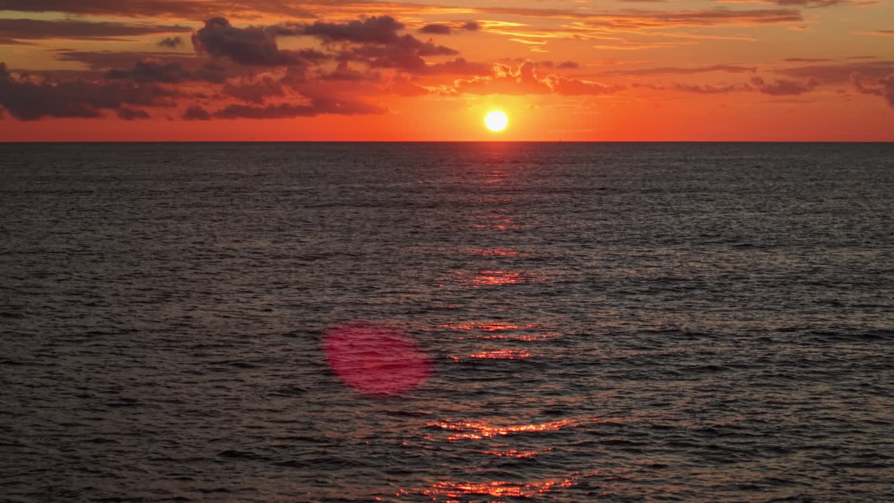 海の水平線に広がる鮮やかなオレンジ色の夕焼け