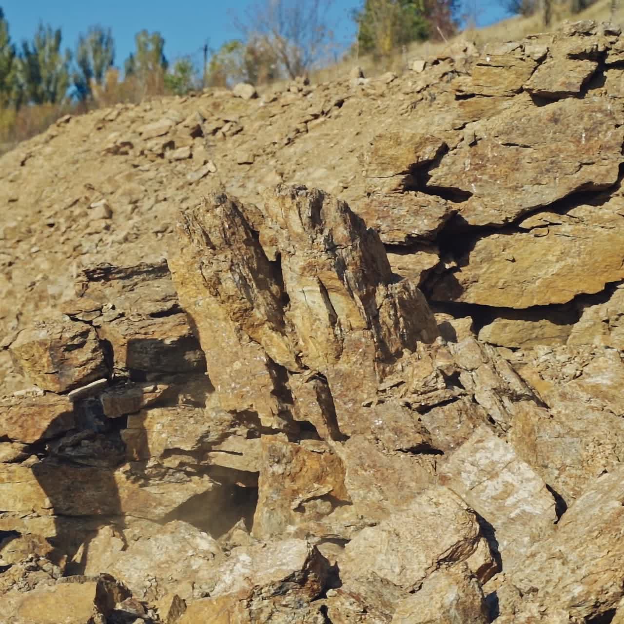 Shirtless bodybuilder splitting rocks with a sledgehammer. Strong man breaking stones with a steel hammer in the mountains. Slow motion.