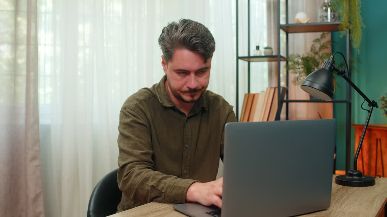 Middleaged man tired finishes laptop work closes eyes sighs exhaustion relief moment at table