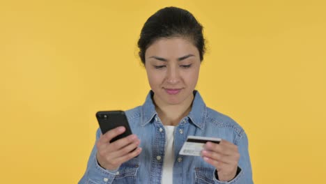 compras en línea en el teléfono inteligente por una joven india, fondo amarillo