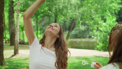 mother with kids blowing soap bubbles outdoors