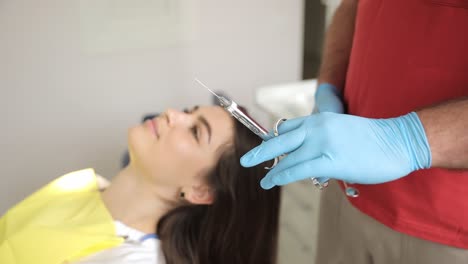 a woman lies in a dental chair as the dentist holds a syringe near her mouth, ready to administer treatment.
