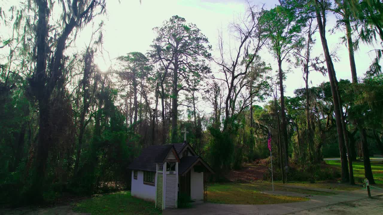 Rising aerial of the world's smallest church, nestled behind tall trees in Townsend, Georgia.