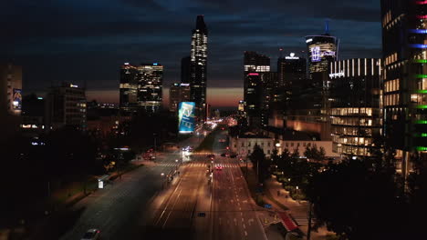 City-street-leading-towards-downtown-skyscrapers.-Silhouettes-of-modern-high-rise-buildings-against-colourful-sky.-Warsaw,-Poland