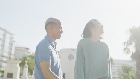 Happy-biracial-couple-embracing-on-promenade,-in-slow-motion