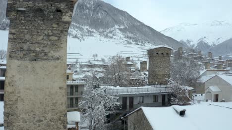 techos de casas y chimeneas y llenos de espesa nieve blanca en mestia, svaneti, georgia en un frío día de invierno con una montaña majestuosa en el fondo - disparo de drones