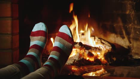 a woman warms her feet by the fireplace