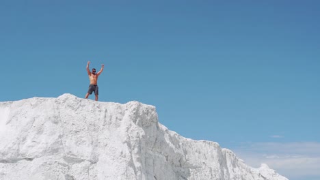 the athlete joyfully celebrates the victory with his hands up. running athlete on top of the mountain