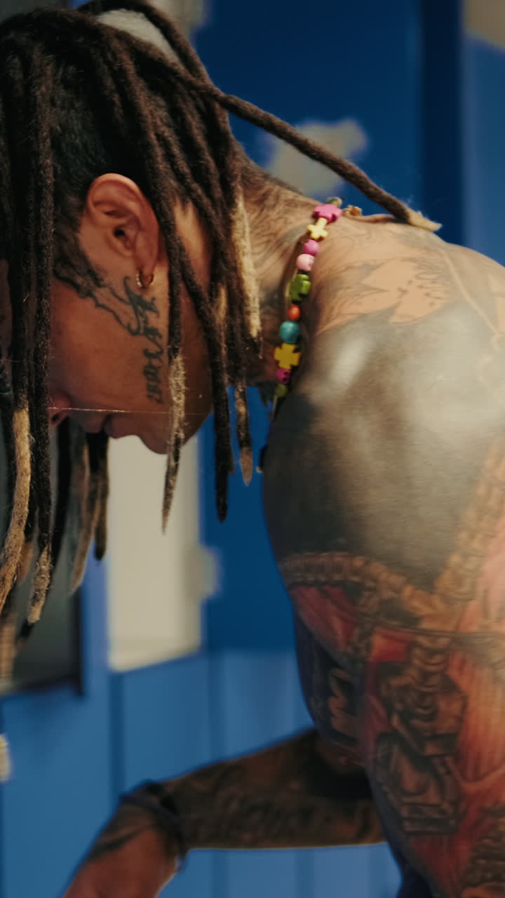 Primo piano di un uomo tatuato con i dreadlock che si veste