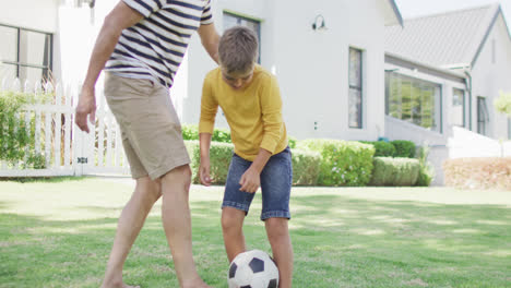 Happy-caucasian-grandfather-and-grandson-playing-football-in-garden,-slow-motion