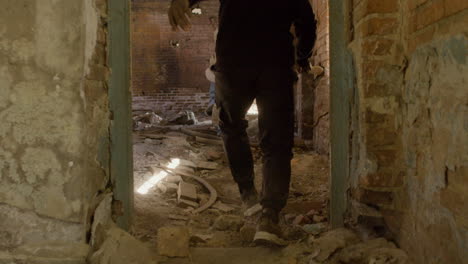 rear view of a man in black balaclava and holding an ax persecuting a redheaded girl in a ruined building