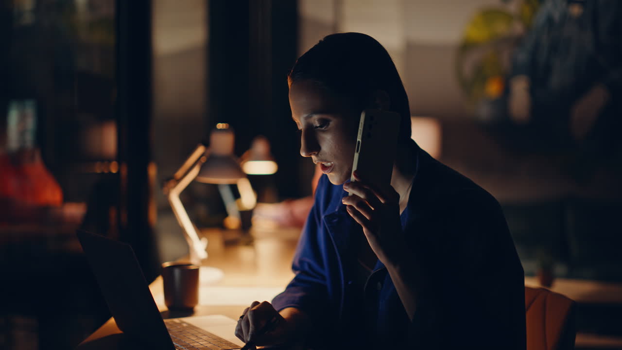 Manager online che chiamano clienti in uffici bui. Donna cordiale che parla al cellulare