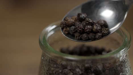 vista de cerca de la pimienta negra entera en cuchara y frasco, ingrediente para la salsa chimichurri