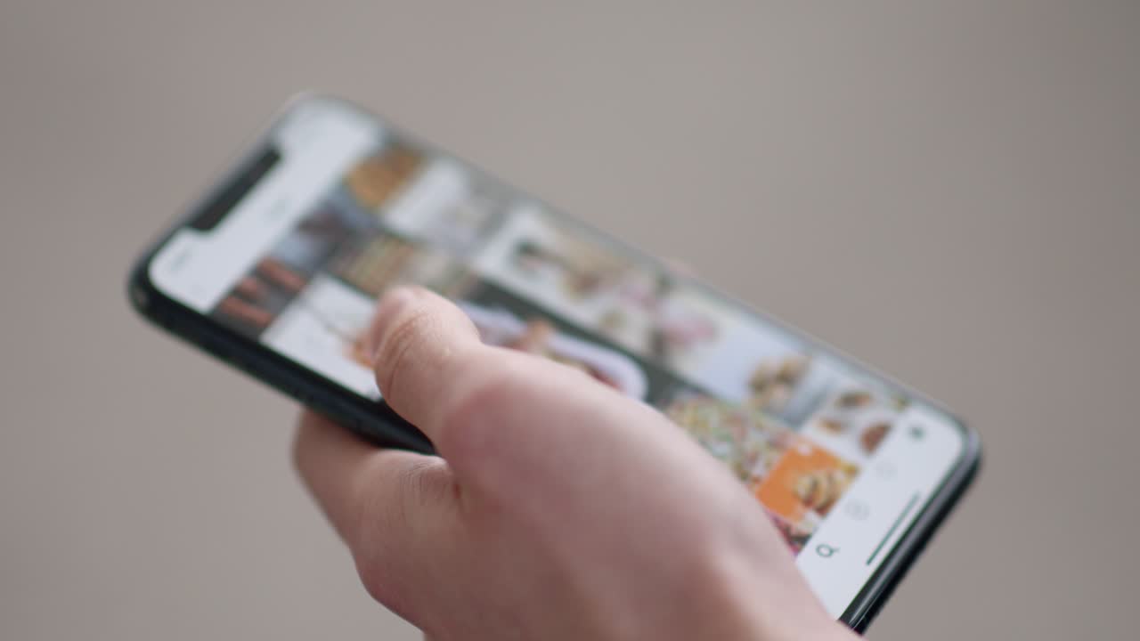 mano sosteniendo un teléfono inteligente, desplazándose a través de imágenes