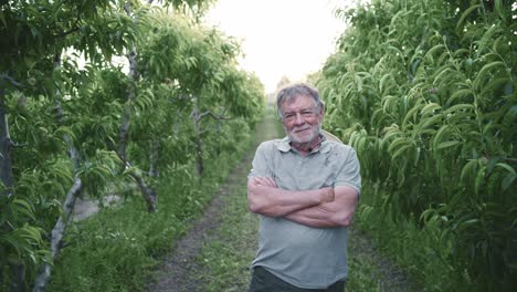 delighted mature male farmer with folded arms standing in countryside