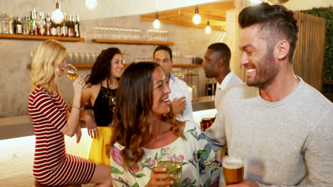 Couple-toasting-drink-glasses-while-friends-chatting-in-background-4K-4k