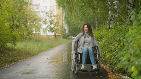 female person with disability moves along path in green park