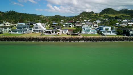 Beach-front-properties-sit-along-the-coast-line-at-high-tide-with-waves-splashing-on-the-rock-wall