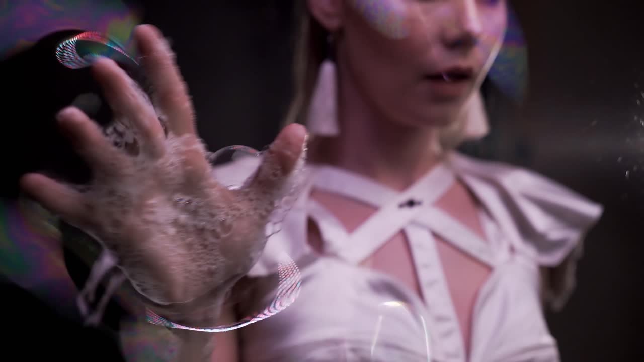 클로즈업 소녀는 비누 거품으로 묘기를 부리며 비누 화면에 젖은 손으로 연기합니다