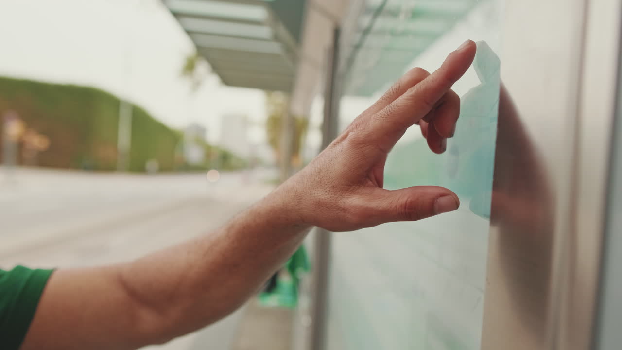 Hand touching a touchscreen display at a bus stop