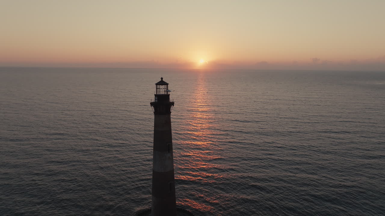Scenic views of sunrise/sunset over the ocean with a lighthouse