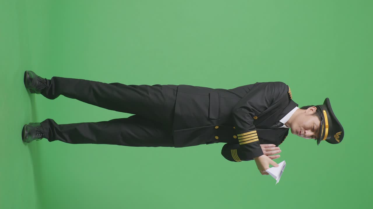 프로 유니폼을 입은 아시아 남성 조종사가 종이 비행기를 발사하고, 제트 모델을 손에 들고, 항공 아카데미 조종사, 녹색 스크린 배경 스튜디오에서 항공기 선장