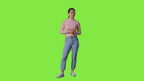 Full-Length-Studio-Portrait-Of-Woman-Thinking-Standing-Against-Green-Screen