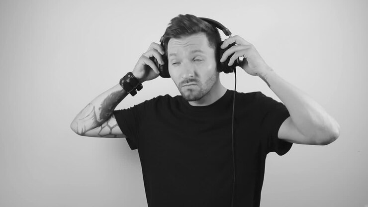 Filmato al rallentatore di un giovane uomo tatuato e attraente che indossa le cuffie e ascolta musica muovendosi, divertendosi ed essendo felice.