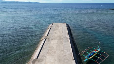 vista idílica del muelle cimentado y el barco tradicional bangka frente a las vastas aguas del océano en filipinas