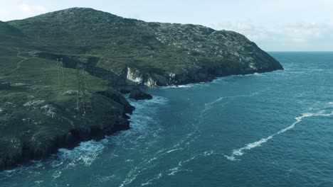 aerial dolly along side a cable car with rugged island costline in background during sunny day