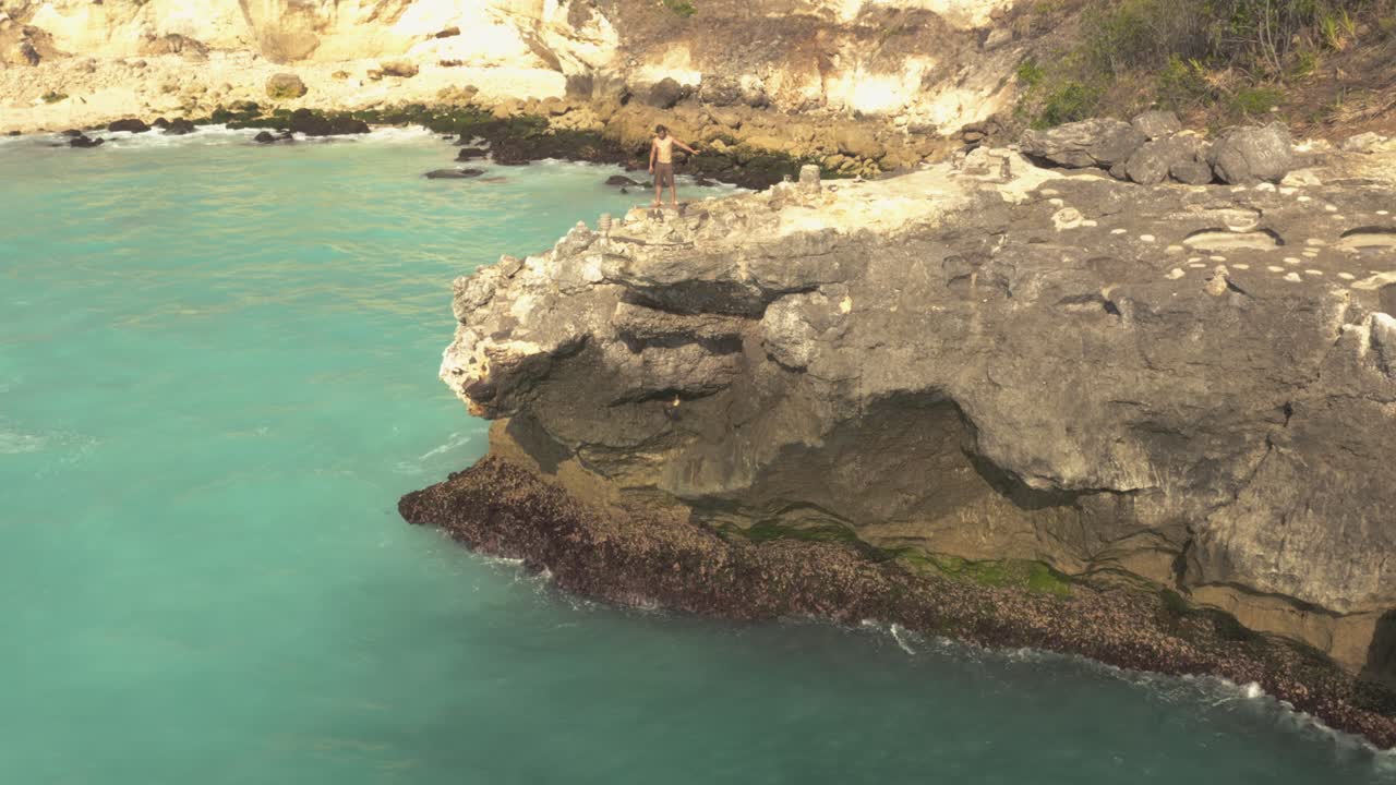 An aerial view of a cliff diver doing a 45 foot belly flop