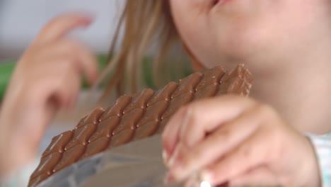 un primer plano de una chica comiendo una barra de chocolate.