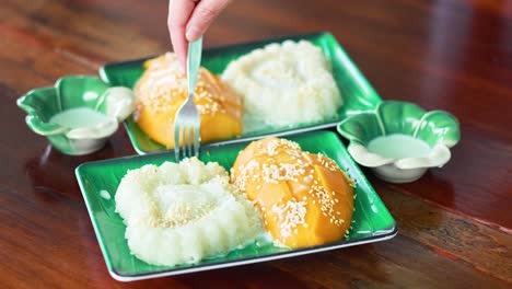 hand serving mango sticky rice with coconut milk