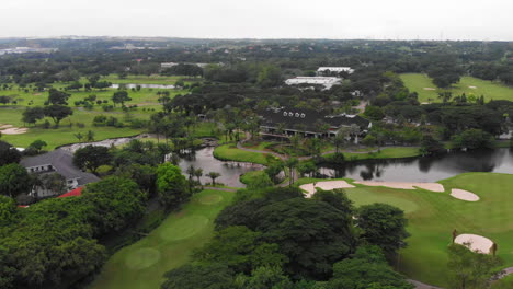 Wide-aerial-view-of-golf-course,-approaching-country-club-house