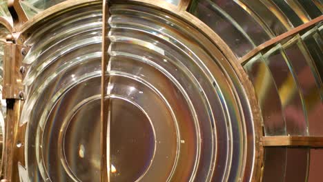 fresnel lens with brass structure, nautical lighthouse tower. detail of the glass lantern with rainbow spectrum. system of lamps and lenses to serve as a navigational aid. old sea searchlight beacon.