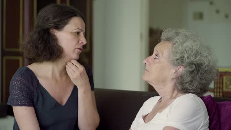 Middle-aged-daughter-and-mother-enjoying-time-together-on-sofa