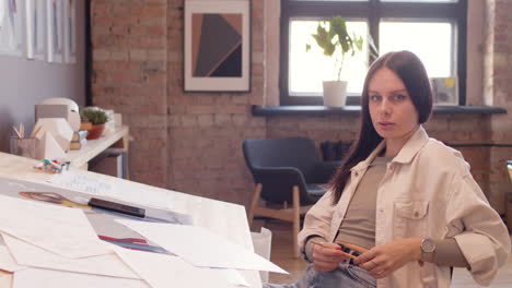 hermosa mujer sonriendo a la cámara mientras se sienta en el escritorio de dibujo en un estudio de animación