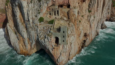 porto flavia: aerial view in orbit of the old mining port of the island of sardinia and the waves hitting the cliff