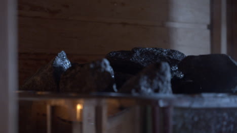 water pouring over steamy rocks in finnish sauna, close up-shot