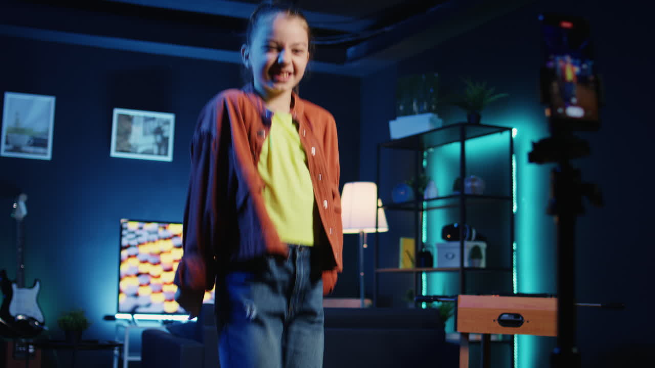 bambino che prende parte alle tendenze, eseguendo coreografia virale su una canzone popolare usando uno smartphone su un treppiede