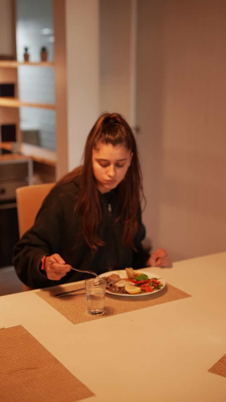 una mujer joven cenando en casa.
