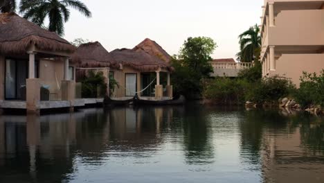 Schöner-Luftdrohnenwagen-In-Aufnahme-Tropischer-Bungalows-Entlang-Eines-Flusses-Innerhalb-Eines-Luxusferienortes-Für-Erwachsene-In-Playa-Del-Carmen,-Riviera-Maya-In-Der-Nähe-Von-Tulum-Mexiko-An-Einem-Sonnigen-Sommertag