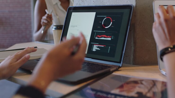 Marketing team look at sales analytics on laptop