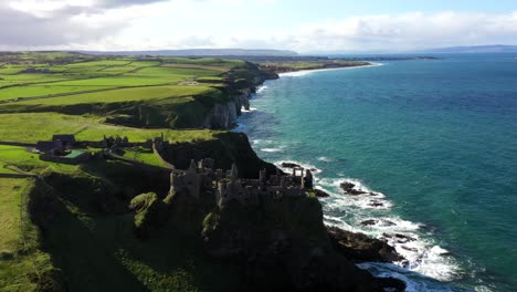 cliffside castle aerial showing dramatic waves crashing below along rugged irish coastline