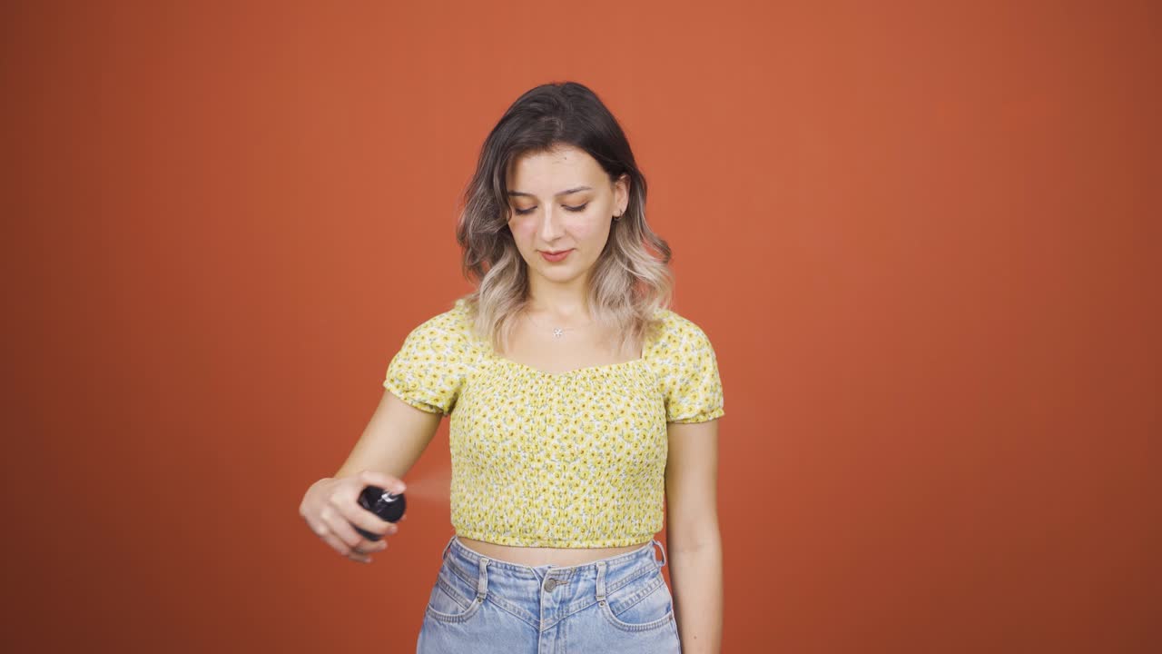 la joven que se pone perfume y huele bien.