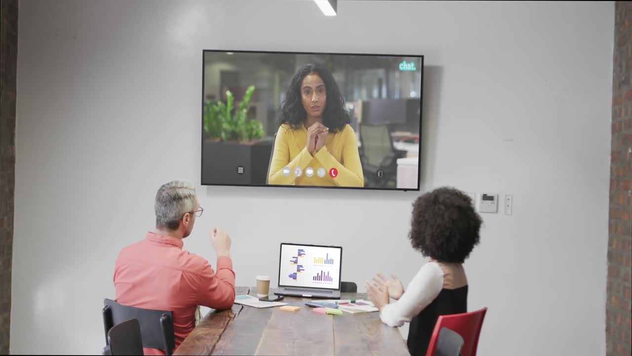 gente de negocios en videoconferencia con una colega afroamericana en la pantalla de televisión