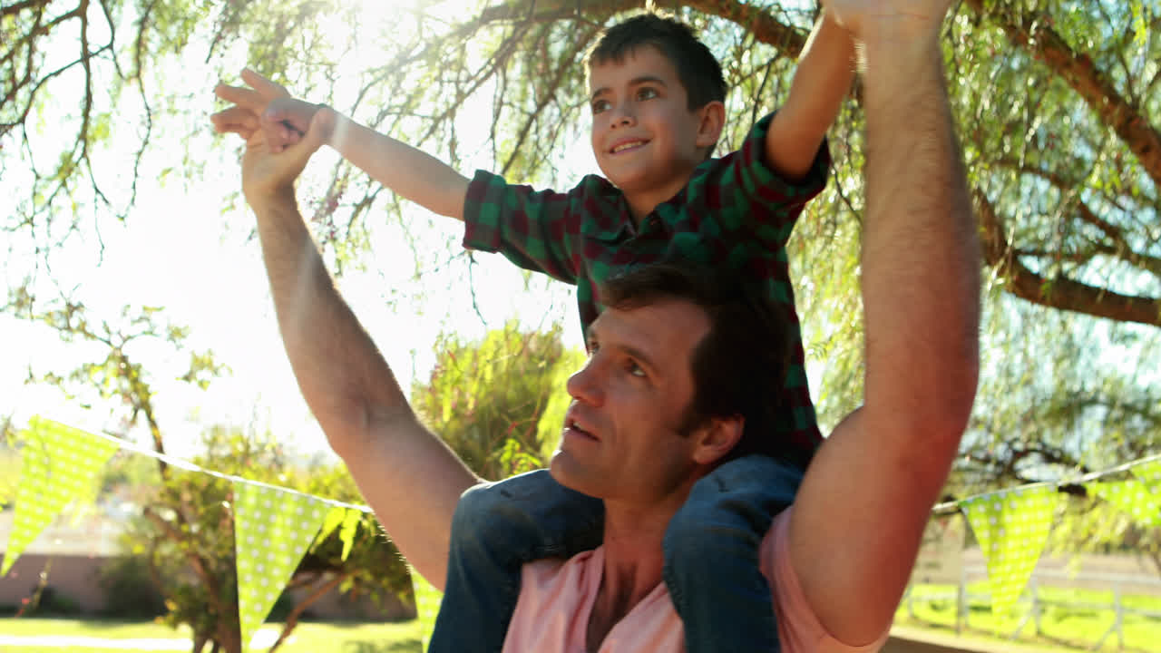 padre feliz cargando a su hijo en el hombro en el parque 4k